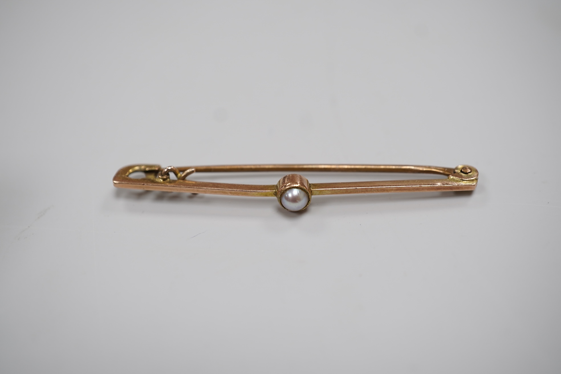 A cased early 20th century 9ct and single stone split pearl set bar brooch, 42mm and a white metal coin bracelet.